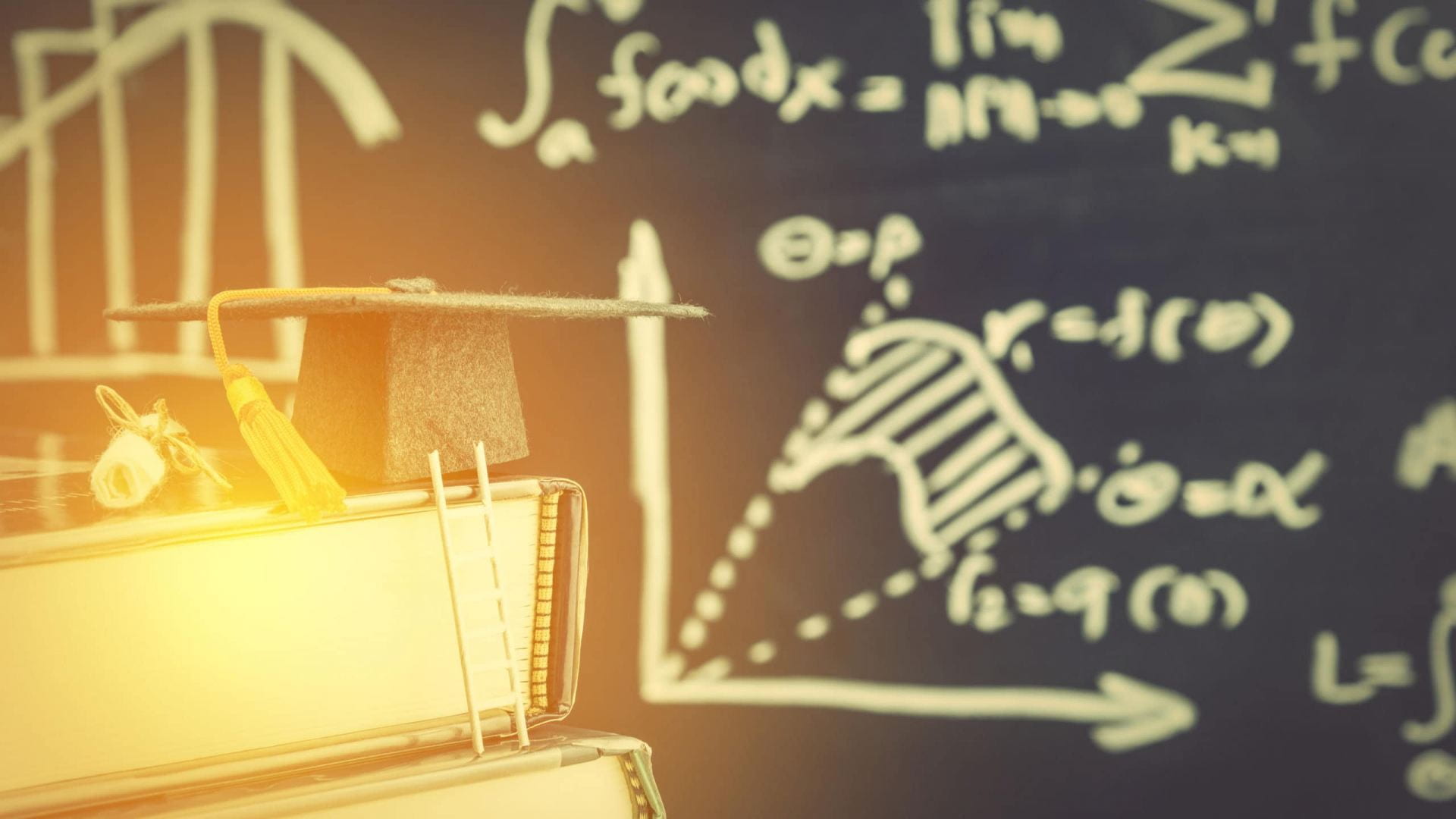 Stock image showing a mortar board, books and a blackboard